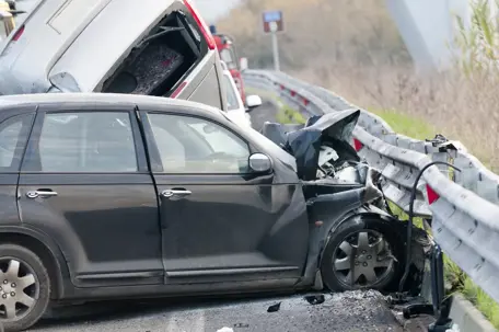 Accidente automovilístico: un coche negro choca contra la barrera de seguridad.